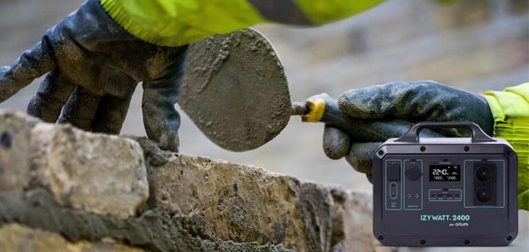 Maçon qui construit un mur à l'aide de sa truelle, ciment, brique et Batterie IZYWATT 2 400